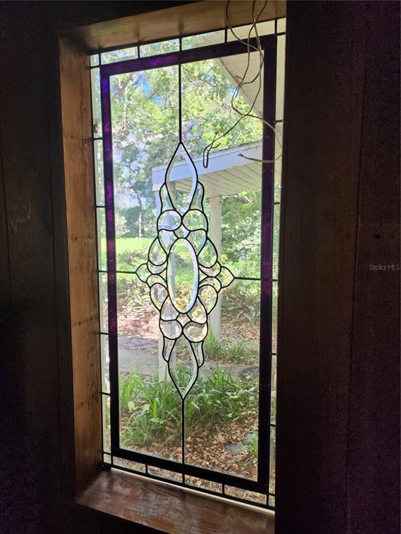 A rectangular stained glass window with a central decorative pattern is set in a wooden frame — 1427 NE 10TH STREET, OCALA, FL