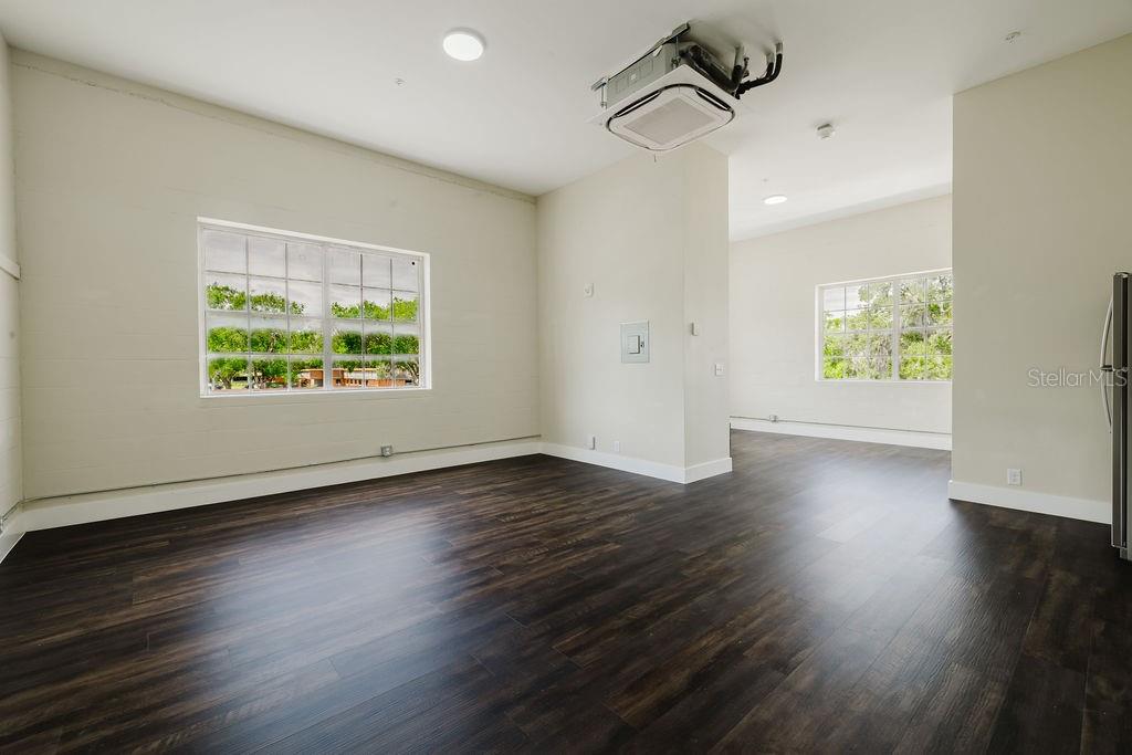 An interior room with dark wood-look flooring, white walls, and a ceiling-mounted HVAC unit — 306 W WISCONSIN AVENUE UNIT 209, DELAND, FL