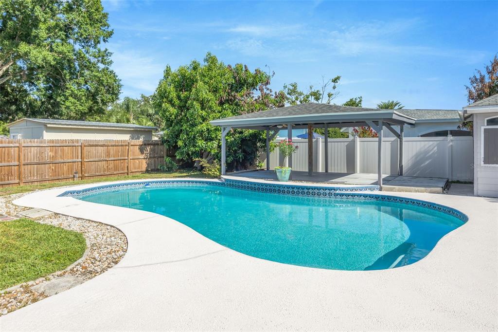 A backyard features a kidney-shaped swimming pool, a covered patio, and a wooden fence — 4608 SOUTHBREEZE DRIVE, TAMPA, FL