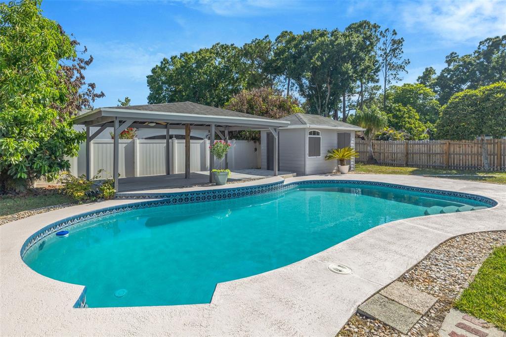 A backyard features a swimming pool, a covered patio area, and a small detached shed — 4608 SOUTHBREEZE DRIVE, TAMPA, FL