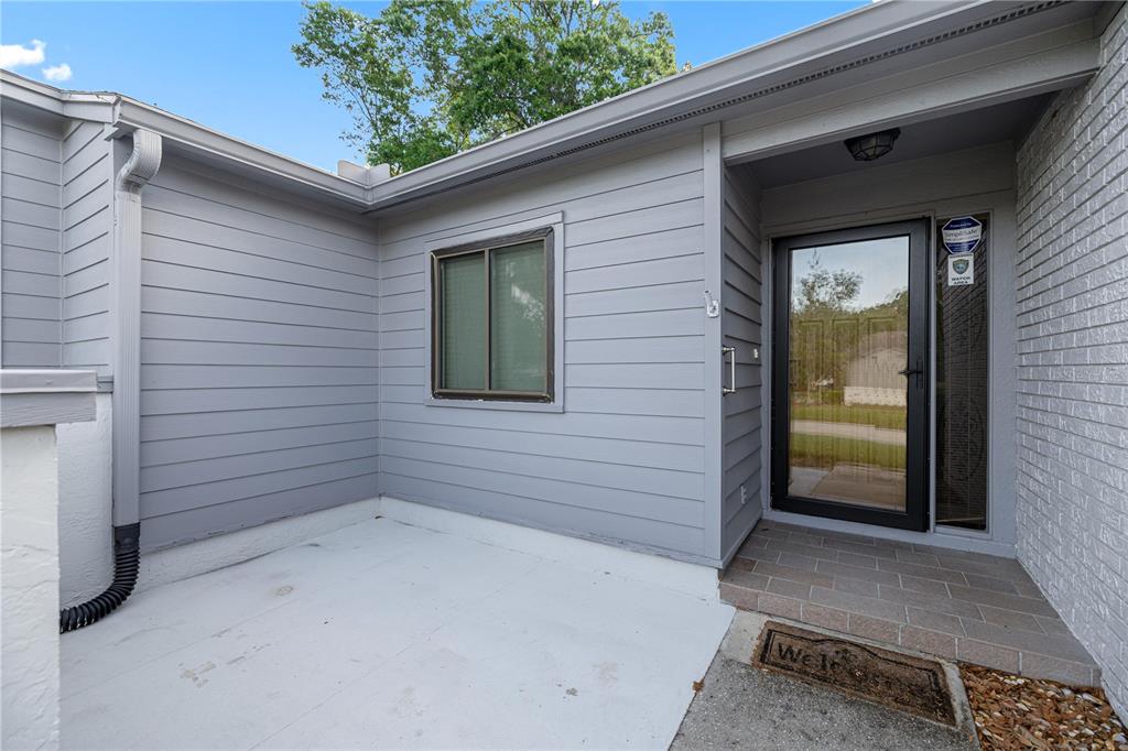 A gray-sided house exterior features a front door, a window, and a concrete porch area — 2052 SE 37TH COURT CIRCLE, OCALA, FL