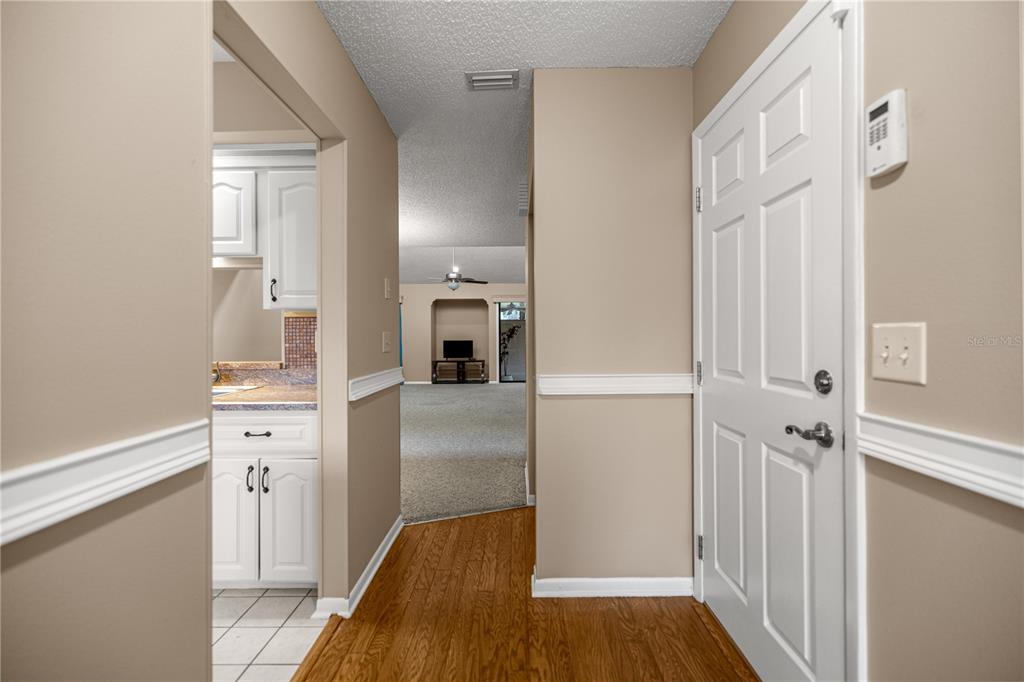 An entryway with hardwood floors leads to a kitchen and a carpeted living area — 2052 SE 37TH COURT CIRCLE, OCALA, FL