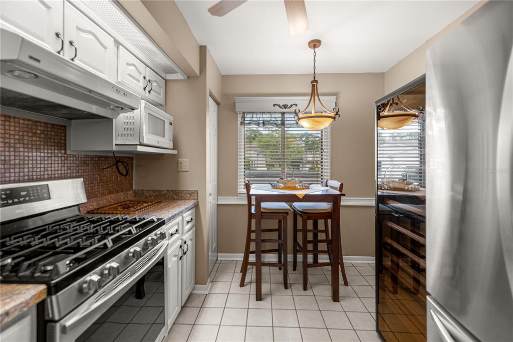 A kitchen features white cabinets, stainless steel appliances, a tile backsplash, and a small dining area — 2052 SE 37TH COURT CIRCLE, OCALA, FL