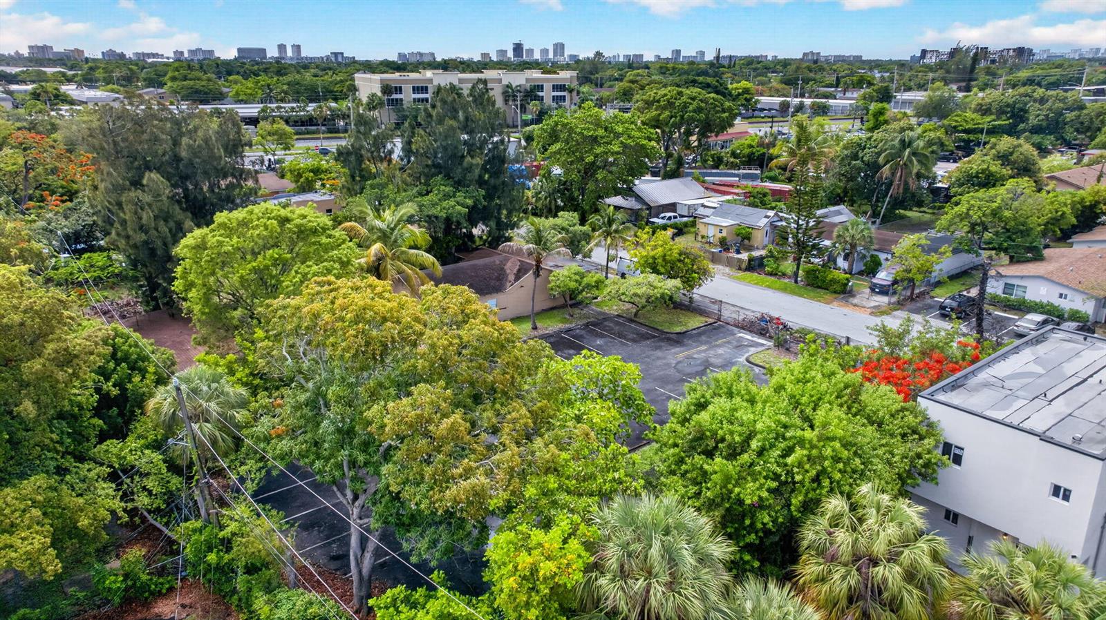An aerial view shows a parking lot surrounded by lush trees and nearby residential buildings — 129 NW 11th Street, Pompano Beach FL 33060, POMPANO BEACH, FL