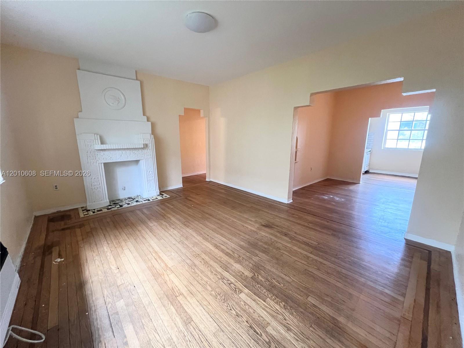 A living room features hardwood floors, a white fireplace, and arched doorways — 1309 Euclid Ave # 7, Miami Beach FL 33139, MIAMI BEACH, FL