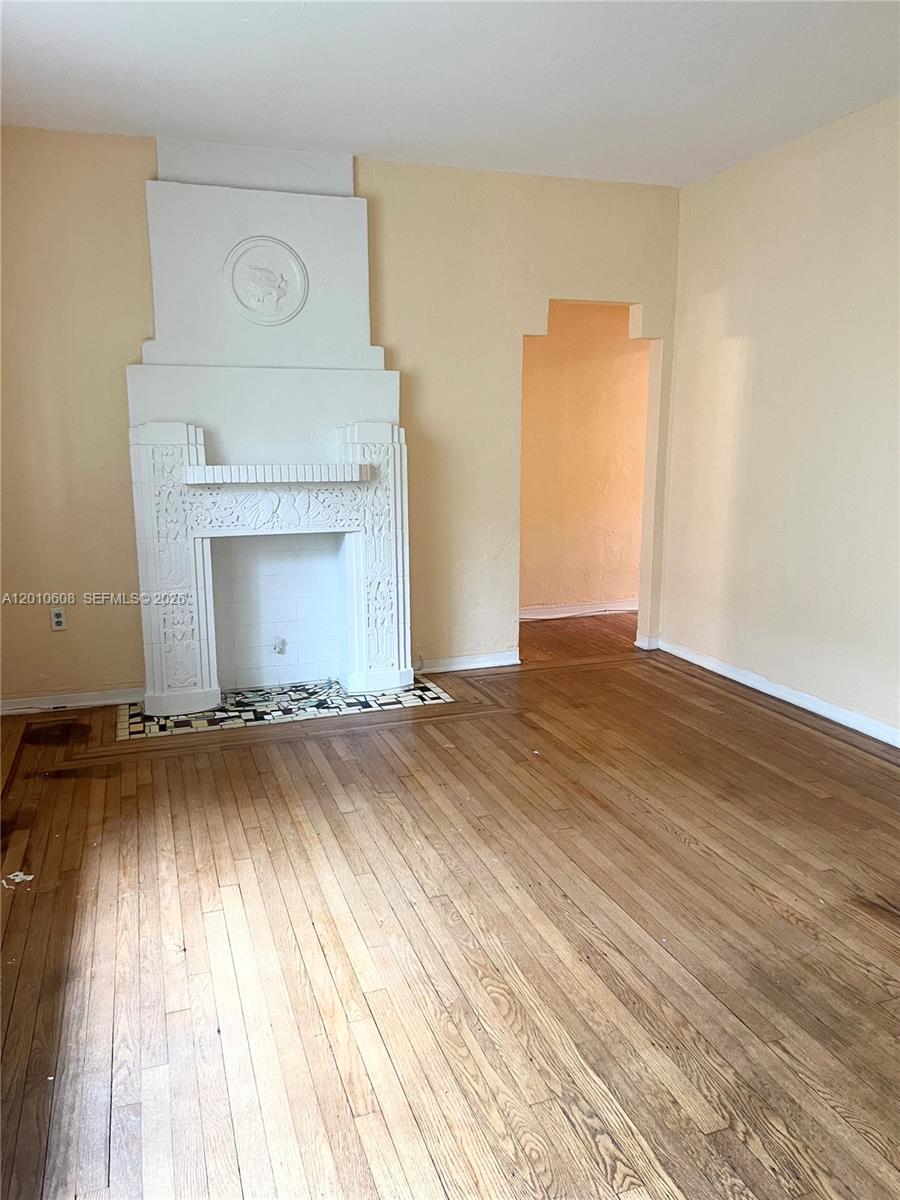 A living room features a white decorative fireplace, hardwood floors, and a doorway — 1309 Euclid Ave # 7, Miami Beach FL 33139, MIAMI BEACH, FL