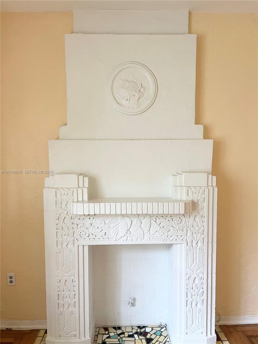 A white, ornate Art Deco fireplace with a relief carving stands against a peach wall — 1309 Euclid Ave # 7, Miami Beach FL 33139, MIAMI BEACH, FL