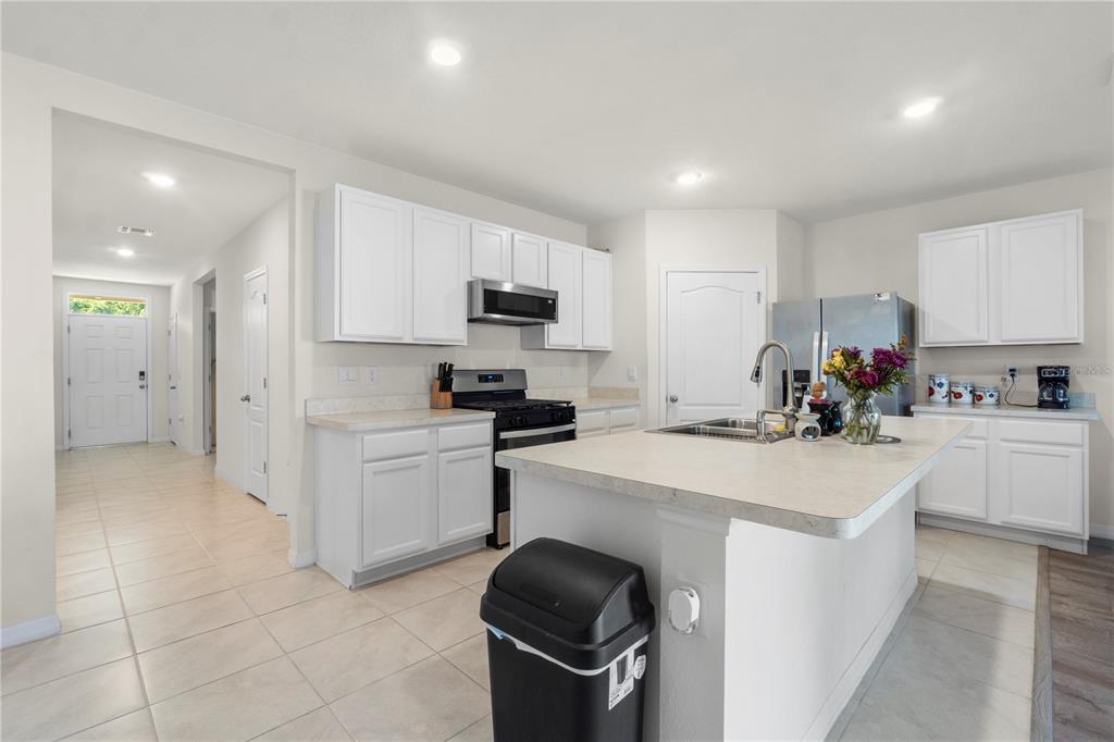 A kitchen with white cabinets, a central island, stainless steel appliances, and light tile flooring — 29320 ARMOYAN BOULEVARD, LEESBURG, FL
