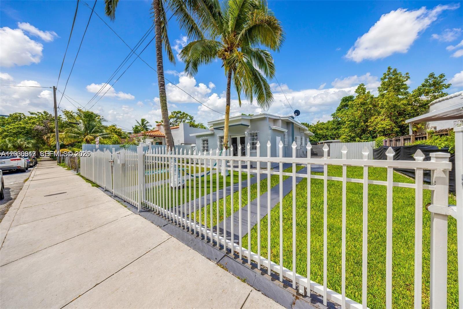 A white metal fence encloses the front yard of a single-story house with palm trees — 3128 NW 3rd Ave, Miami FL 33127, MIAMI, FL