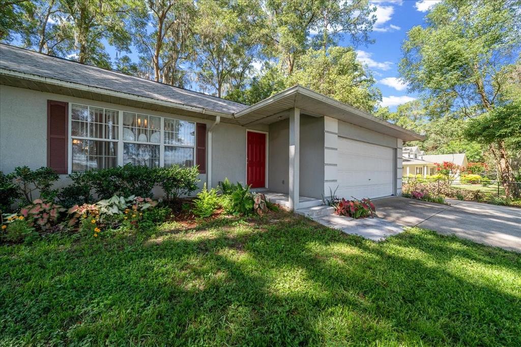 A single-story house with a red front door, white garage, and a landscaped front yard — 3100 NE 35TH STREET, OCALA, FL