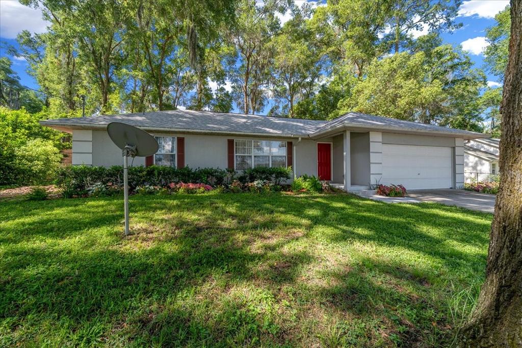A single-story house with a gray exterior, red front door, and a two-car garage — 3100 NE 35TH STREET, OCALA, FL