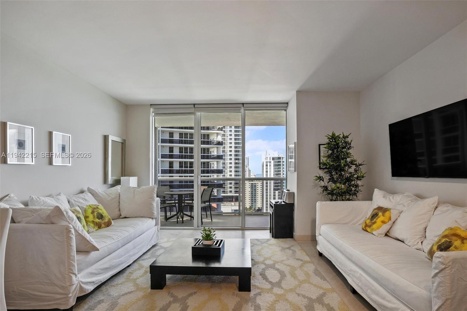 A living room features two white sofas, a black coffee table, and a balcony view — 1830 S OCEAN DR # 2110, Hallandale Beach FL 33009, HALLANDALE BEACH, FL