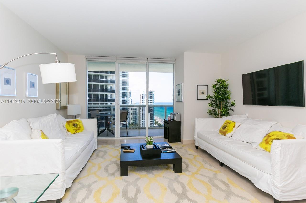 A living room features two white sofas, a black coffee table, and a balcony view — 1830 S OCEAN DR # 2110, Hallandale Beach FL 33009, HALLANDALE BEACH, FL