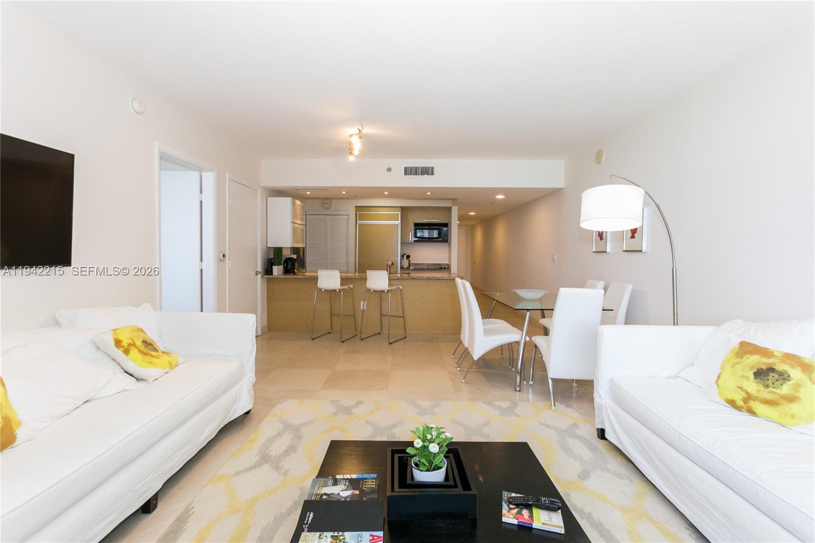 A living room with white sofas, a dining area, and an open kitchen with barstools — 1830 S OCEAN DR # 2110, Hallandale Beach FL 33009, HALLANDALE BEACH, FL