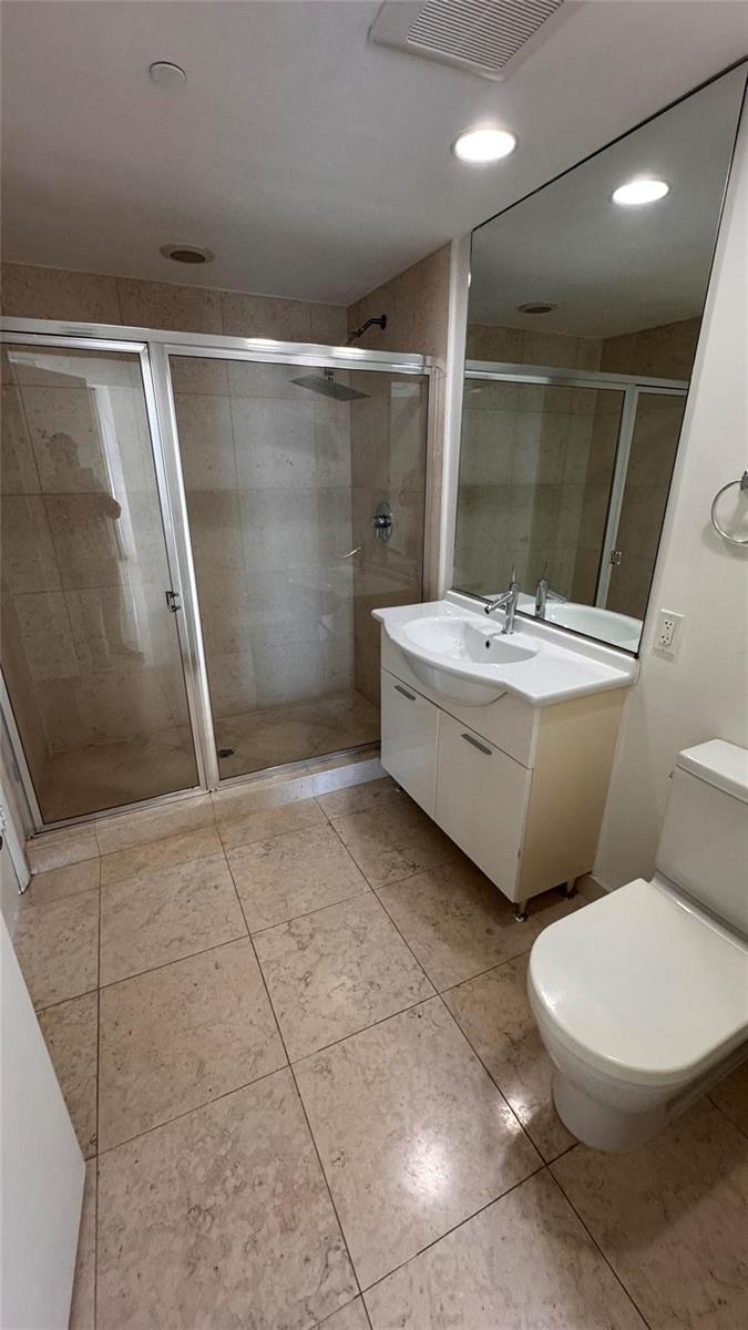 A bathroom features a glass-enclosed shower, a white vanity with a sink, and tiled flooring — 475 Brickell Avenue # 4913, Miami FL 33131, MIAMI, FL