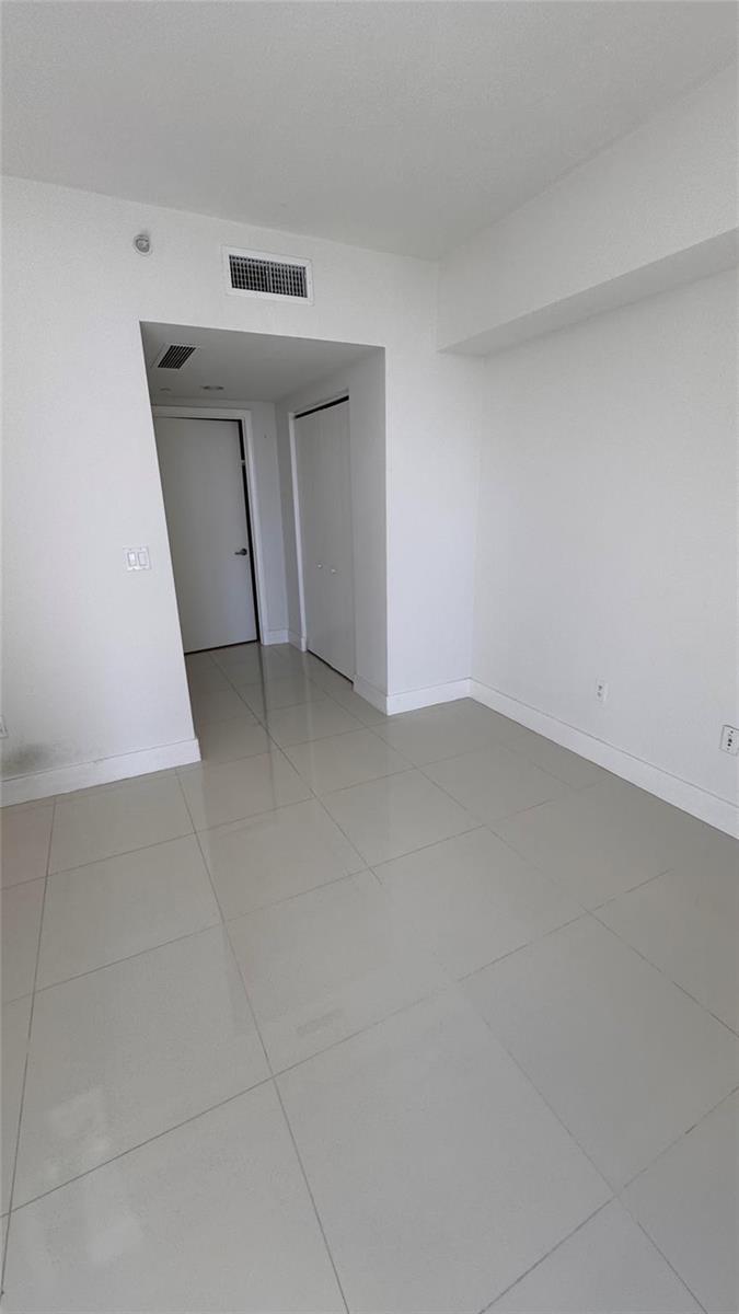 An empty room with white walls, light-colored tile flooring, and two closed white doors — 475 Brickell Avenue # 4913, Miami FL 33131, MIAMI, FL