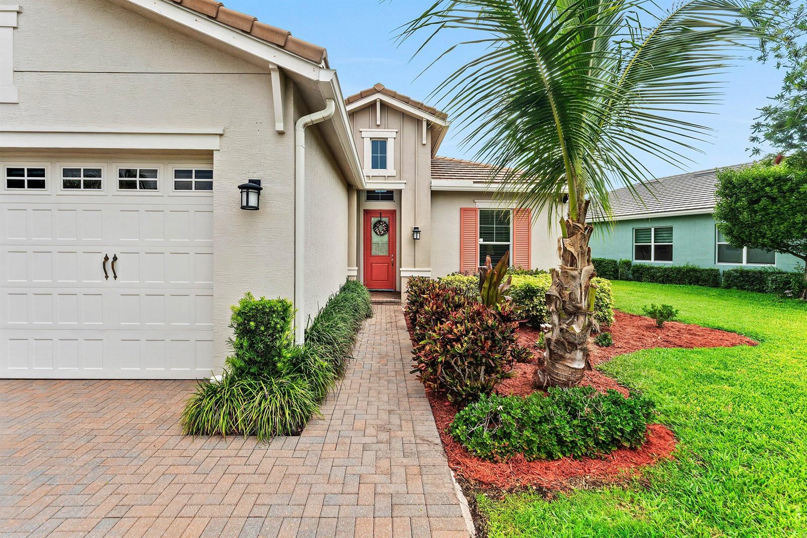 A single-story house features a red front door, a brick walkway, and a palm tree — 5921 Switchgrass Lane, FL 33470, FL