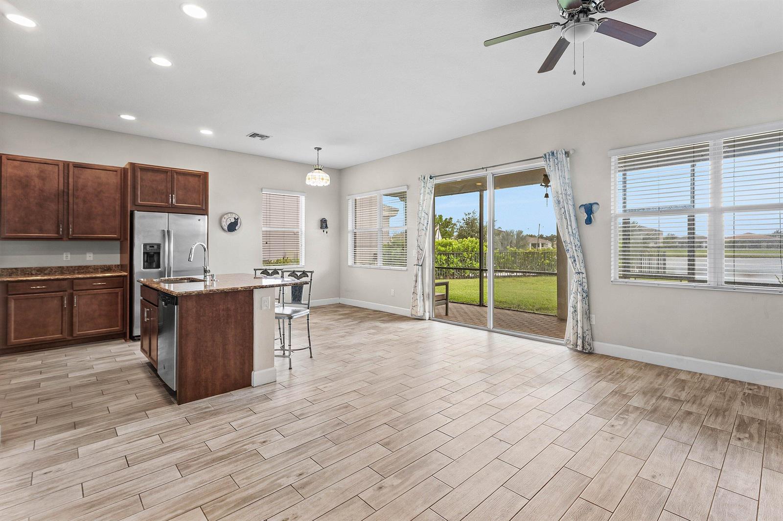 A kitchen with wood cabinets and a granite island opens to a bright living area — 5921 Switchgrass Lane, FL 33470, FL