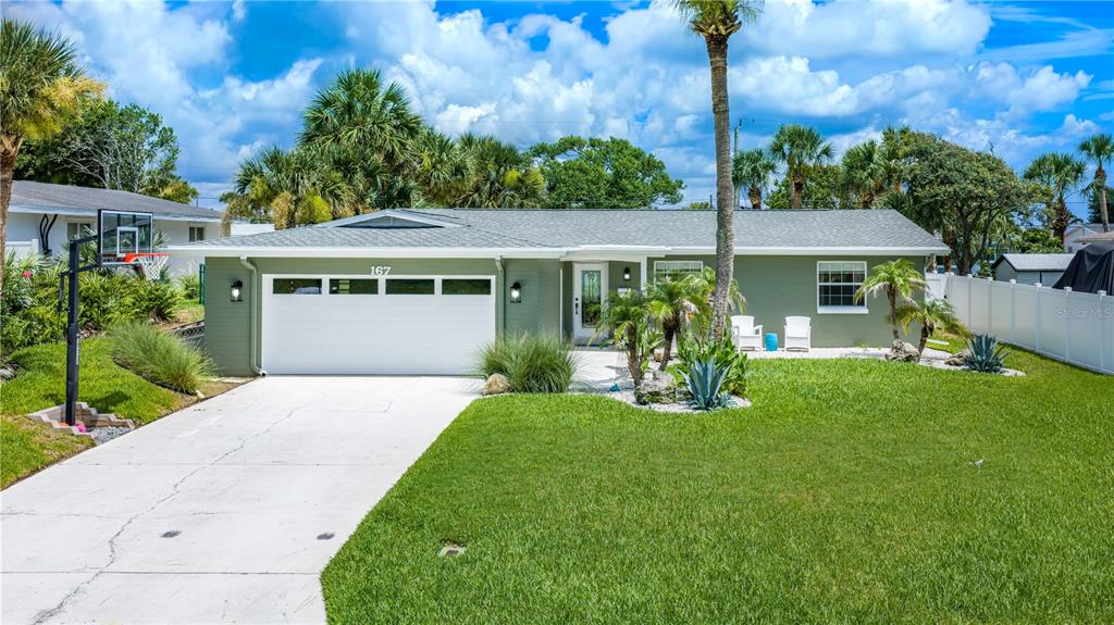 A single-story green house with a white garage door, driveway, and front lawn — 167 ROYAL DUNES BOULEVARD, ORMOND BEACH, FL