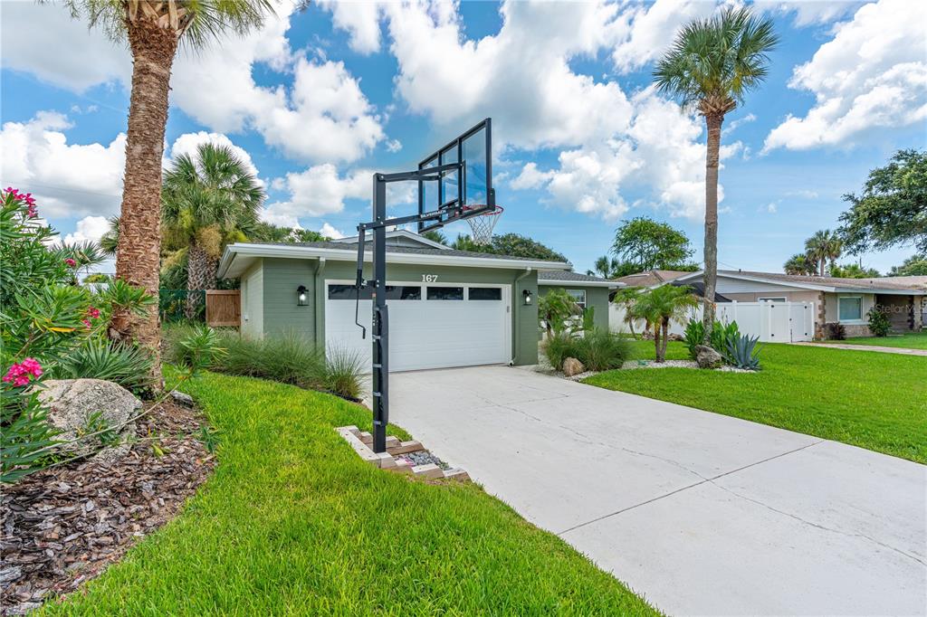 A green house with a white garage door and a basketball hoop on the driveway — 167 ROYAL DUNES BOULEVARD, ORMOND BEACH, FL