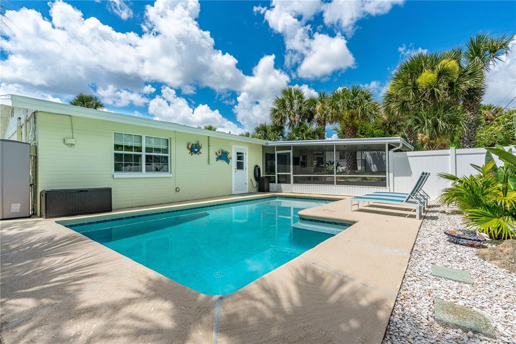 A backyard features a swimming pool, a light green house, and a screened-in patio area — 167 ROYAL DUNES BOULEVARD, ORMOND BEACH, FL