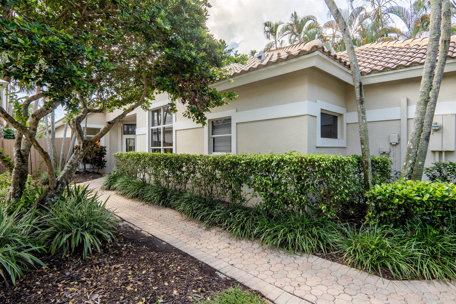 A paved walkway leads to the entrance of a beige house with a tiled roof — 6670 NW 27th Avenue, Boca Raton FL 33496, BOCA RATON, FL