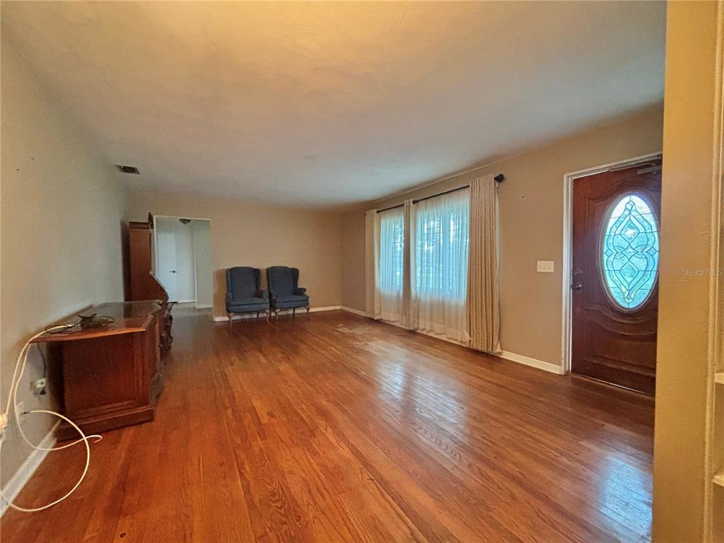 A living room features hardwood floors, two blue armchairs, and a front door with glass — 347 S 2ND STREET, EAGLE LAKE, FL