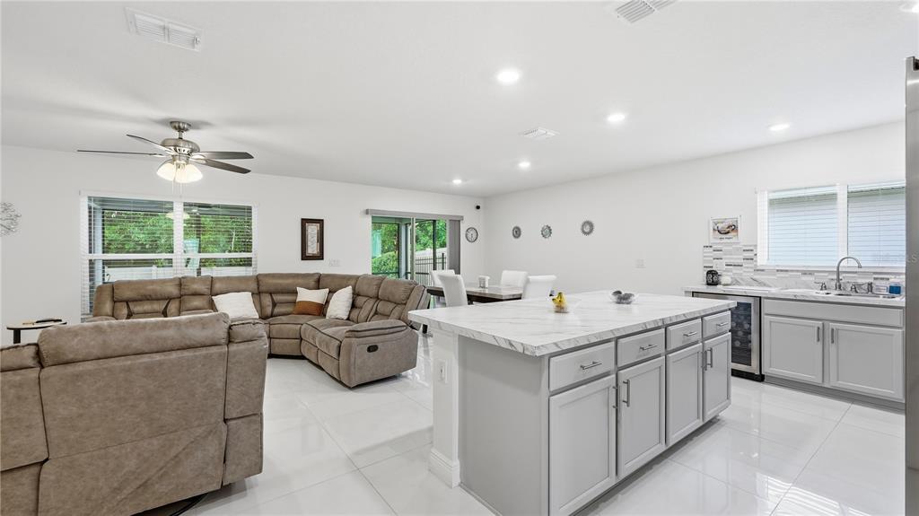 An open-concept kitchen and living area features a large island, gray cabinetry, and tile flooring — 2457 BULRUSH DRIVE, ST CLOUD, FL