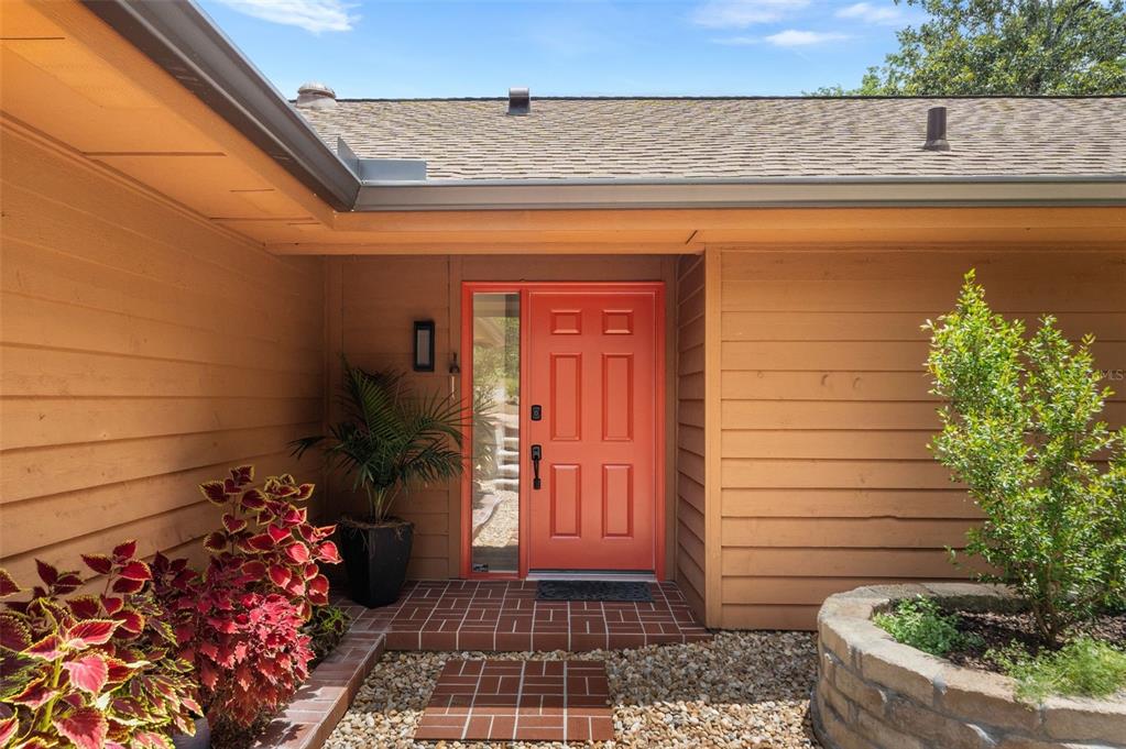 An exterior view shows a red front door with a sidelight and tan siding — 11715 NW 122ND TERRACE, ALACHUA, FL