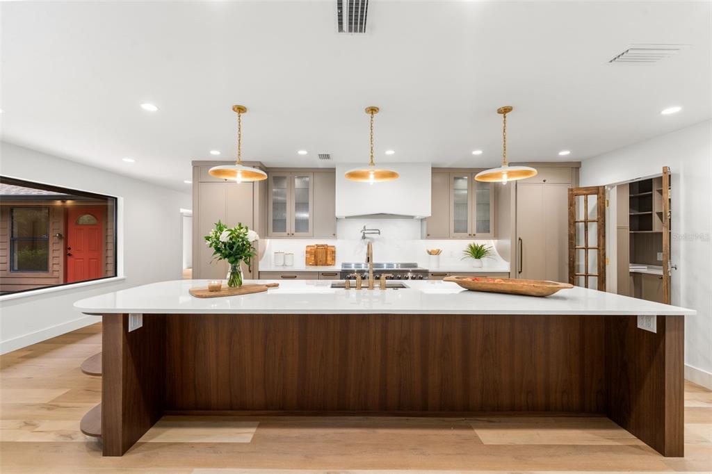 A modern kitchen features a large wood-paneled island with a white countertop and three pendant lights — 11715 NW 122ND TERRACE, ALACHUA, FL
