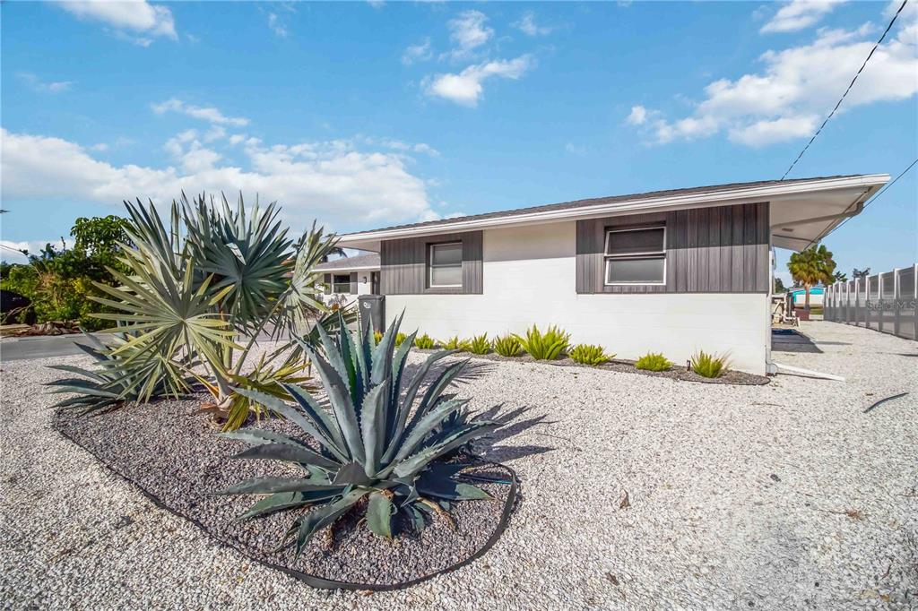 A white house with gray accents features a gravel yard with agave and palm plants — 4012 99TH STREET W, BRADENTON, FL