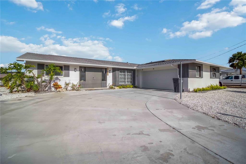 A single-story house with a white exterior, a gray roof, and a large concrete driveway — 4012 99TH STREET W, BRADENTON, FL
