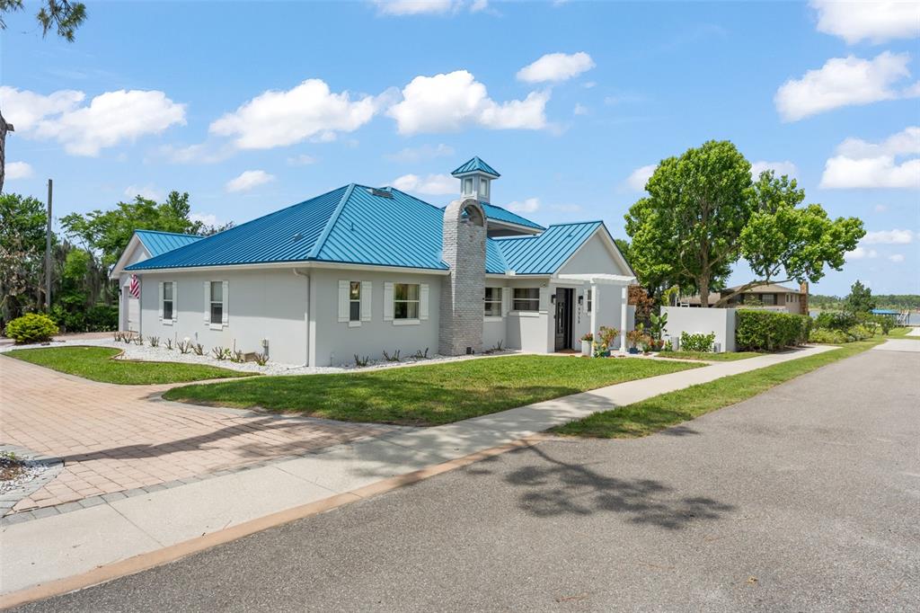 A single-story house with a blue metal roof, gray exterior, and a brick chimney — 9958 KILGORE ROAD, ORLANDO, FL