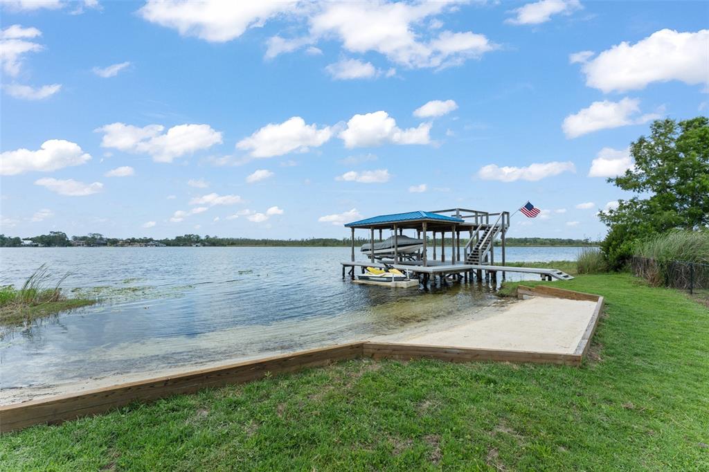 A wooden dock with a boat lift and a small sandy beach area by a lake — 9958 KILGORE ROAD, ORLANDO, FL
