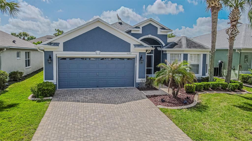 A blue single-story house with a paved driveway, a two-car garage, and a landscaped yard — 10312 OLD TAMPA BAY DRIVE, SAN ANTONIO, FL