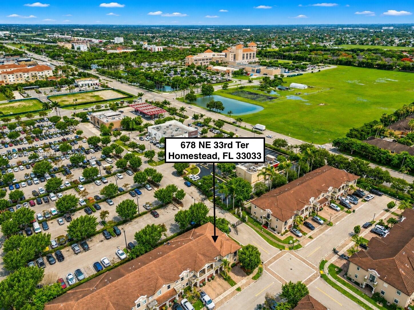 An aerial view shows a residential townhouse complex with a parking lot and surrounding neighborhood — 678 NE 33rd Ter, Homestead FL 33033, HOMESTEAD, FL