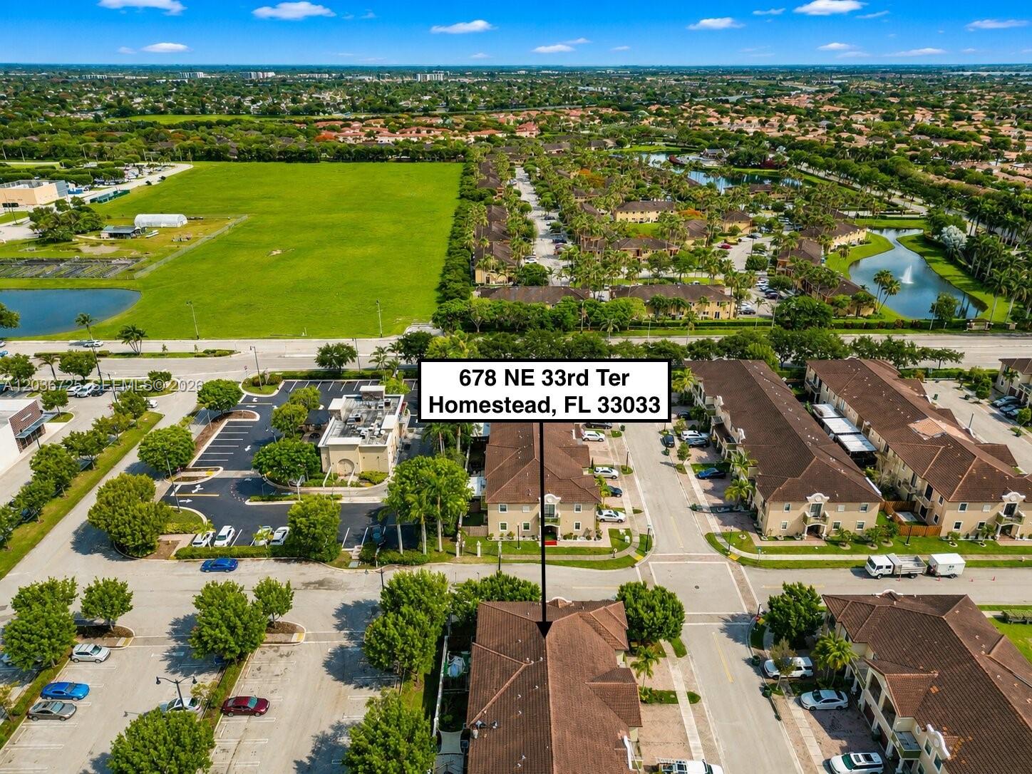 An aerial view shows a residential neighborhood with townhomes, parking lots, and a large field — 678 NE 33rd Ter, Homestead FL 33033, HOMESTEAD, FL