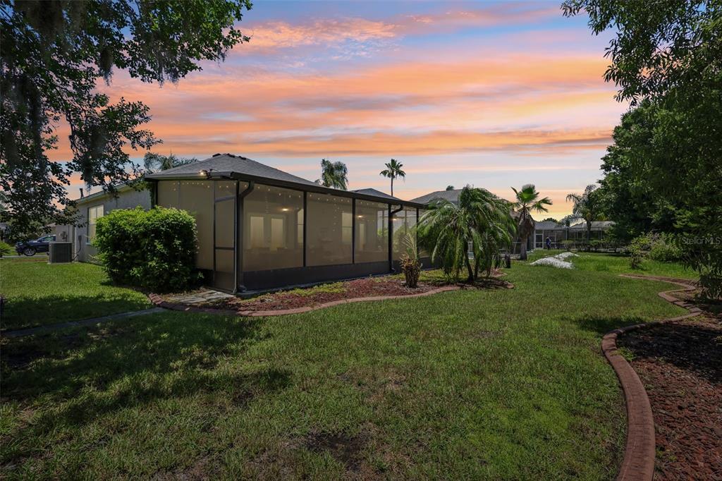 A screened-in patio attached to the back of a house overlooks a grassy backyard — 1628 CROSSVINE COURT, TRINITY, FL