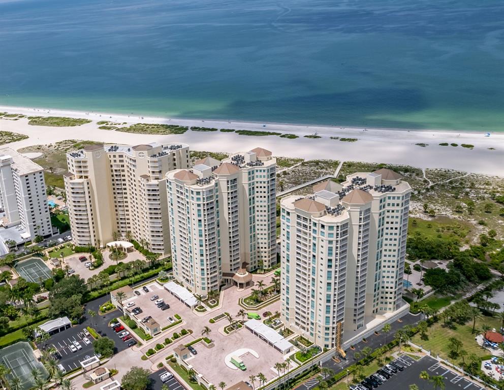 An aerial view shows three tall residential towers situated on a beach near the ocean — 1180 GULF BOULEVARD UNIT 1202, CLEARWATER BEACH, FL