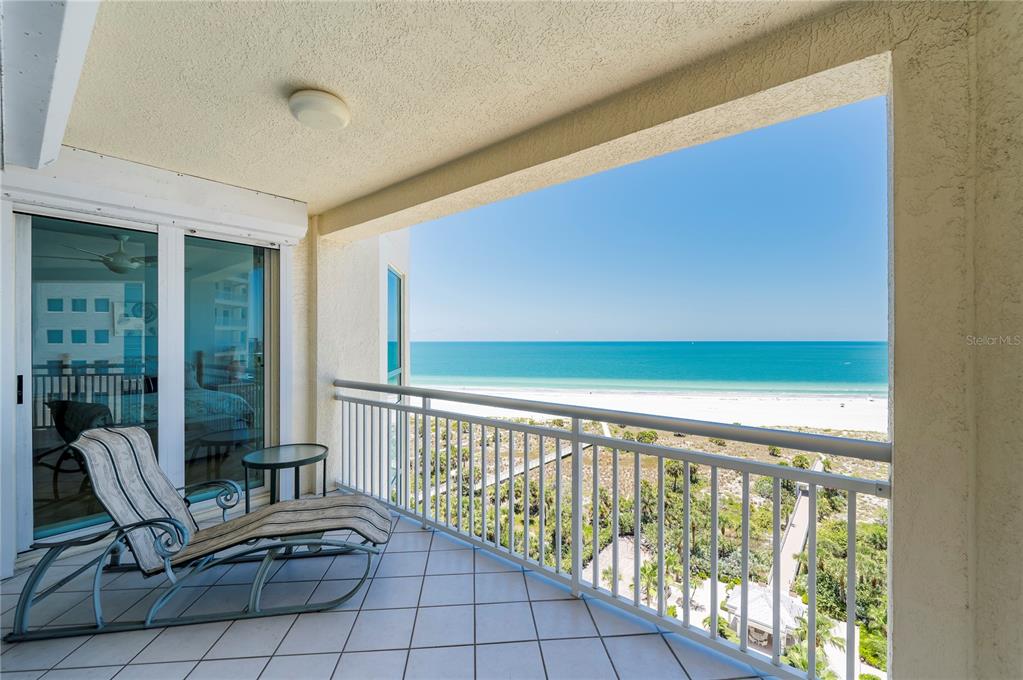 A tiled balcony with a lounge chair overlooks a sandy beach and the ocean — 1180 GULF BOULEVARD UNIT 1202, CLEARWATER BEACH, FL