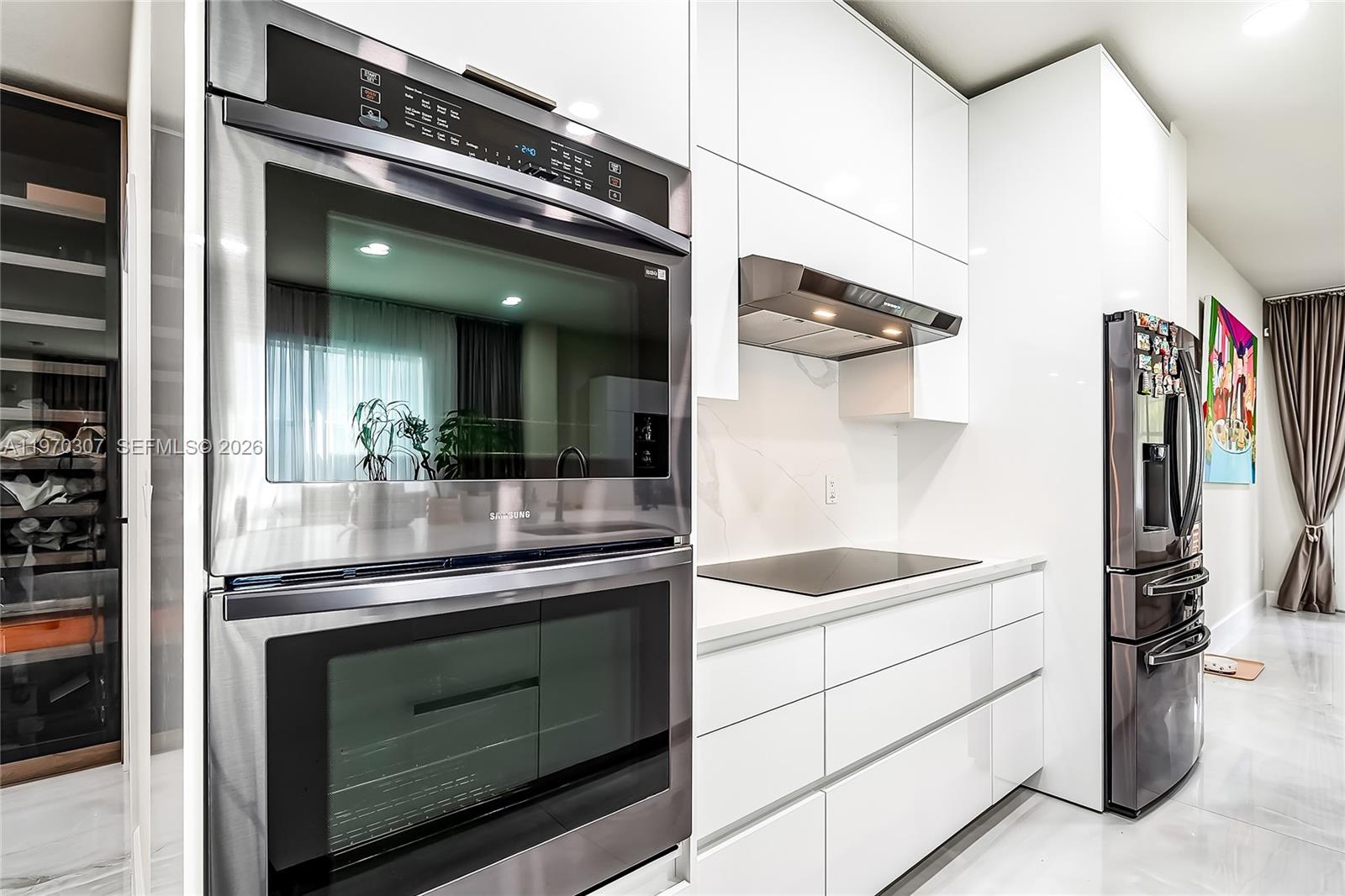 A modern kitchen features white cabinetry, stainless steel appliances, and a marble-style backsplash — 4566 Ficus St, Hollywood FL 33021, HOLLYWOOD, FL