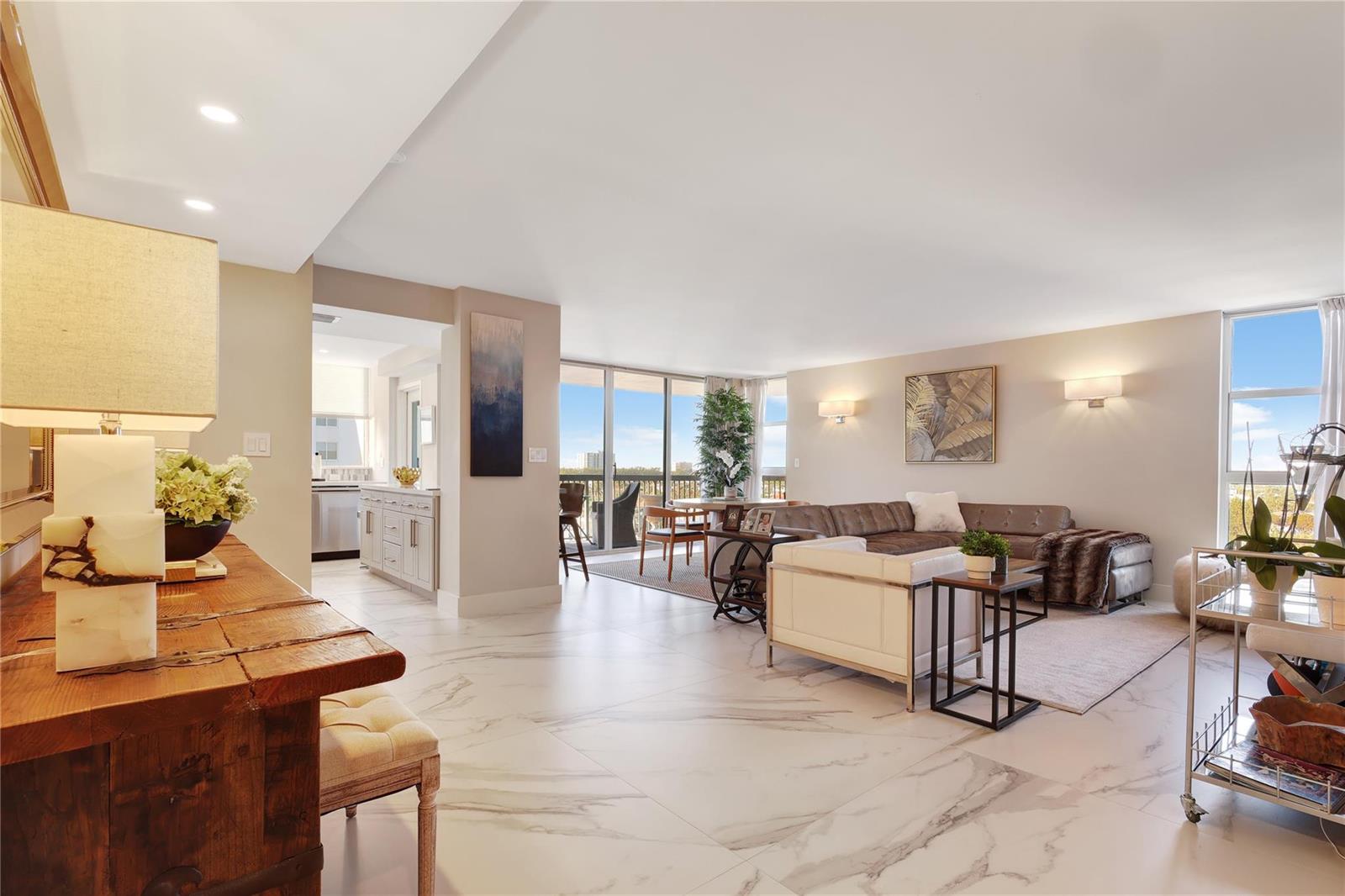 A spacious living room with marble floors, a sectional sofa, and a balcony view — 1361 S Ocean Boulevard # 910, Pompano Beach FL 33062, POMPANO BEACH, FL