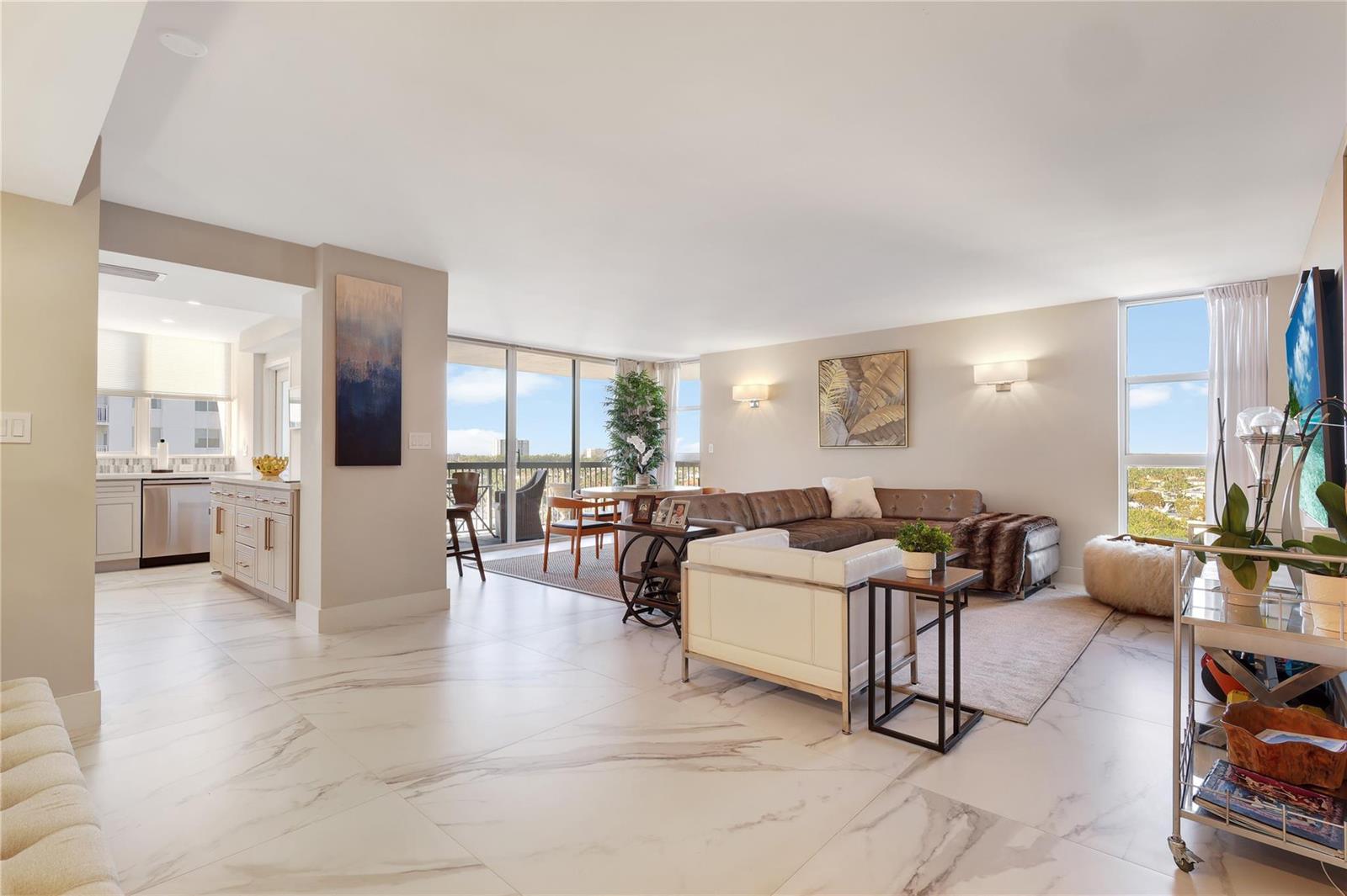A bright, open-concept living room and kitchen featuring marble floors and floor-to-ceiling windows — 1361 S Ocean Boulevard # 910, Pompano Beach FL 33062, POMPANO BEACH, FL