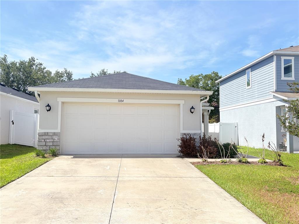 A single-story house with a two-car garage and stone accents on the front facade — 1084 PAPAYA CIRCLE, DAVENPORT, FL