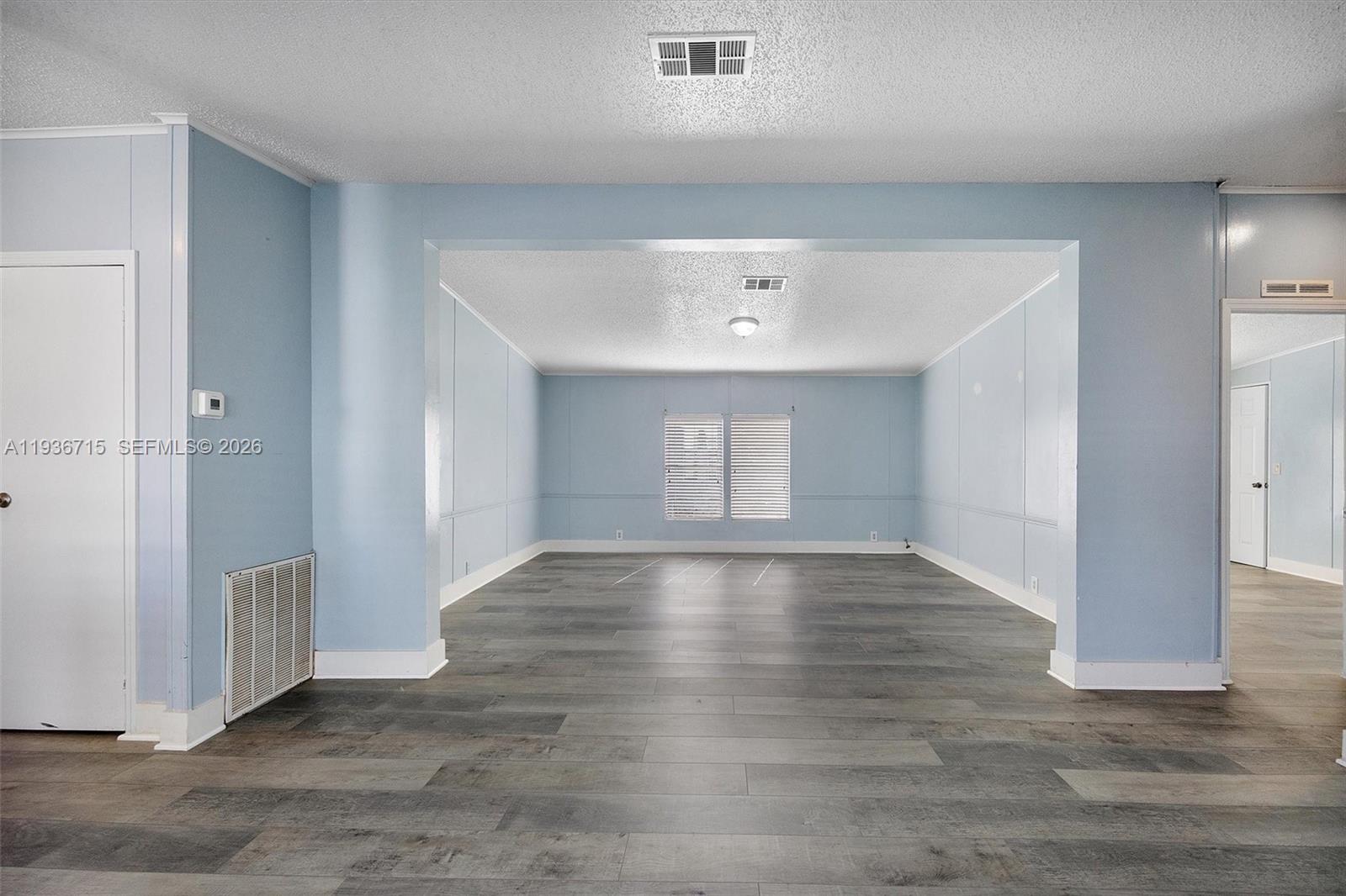 An empty room features light blue walls, gray wood-look flooring, and a white ceiling — 19800 SW 180th Ave Lot 222, Miami FL 33187, MIAMI, FL