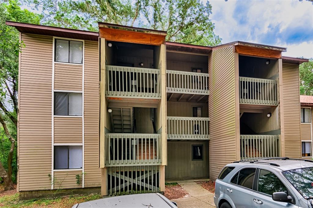 A three-story apartment building with tan horizontal siding and open-air stairwells — 105 SE 16TH AVENUE UNIT N103, GAINESVILLE, FL