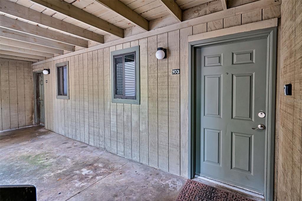 The exterior of a building shows a covered walkway with two doors and two windows — 105 SE 16TH AVENUE UNIT N103, GAINESVILLE, FL