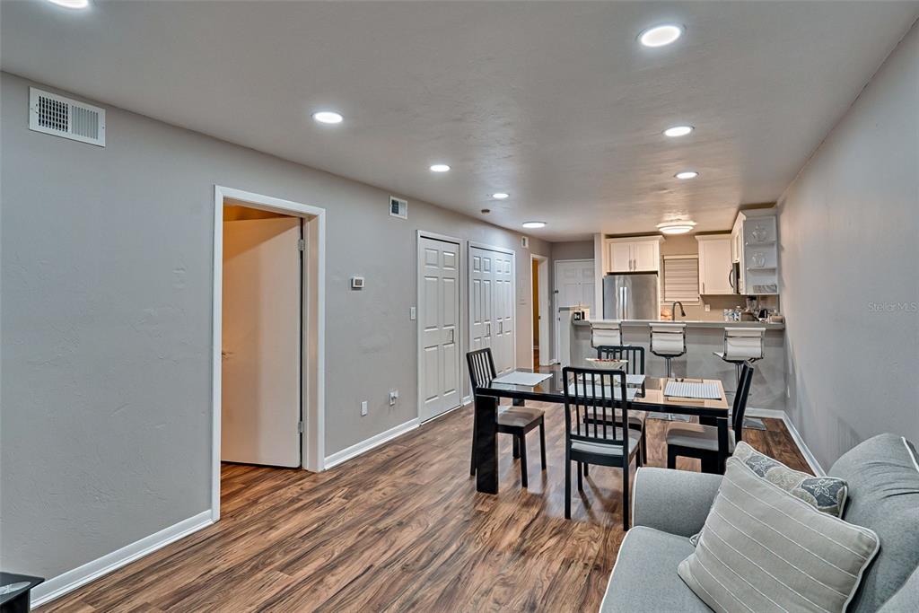 An open-concept living and dining area features wood-look flooring, recessed lighting, and a kitchen bar — 105 SE 16TH AVENUE UNIT N103, GAINESVILLE, FL