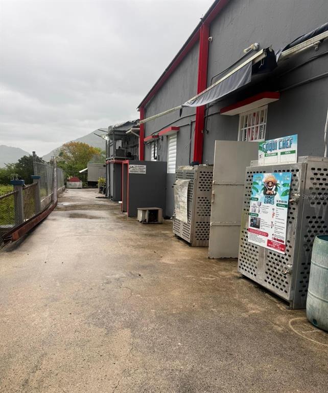 An exterior view shows a concrete walkway alongside a gray building with metal storage cages — PR 14 BARRIO MATON, CAYEY, PR