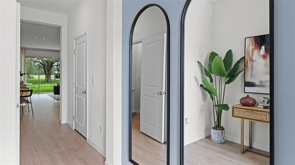 A hallway features light wood flooring, arched mirrors, a potted plant, and a console table — 3516 CHROMA STREET, ORLANDO, FL